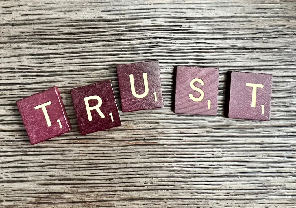 Wooden Scrabble tiles spelling the word TRUST on weathered wood